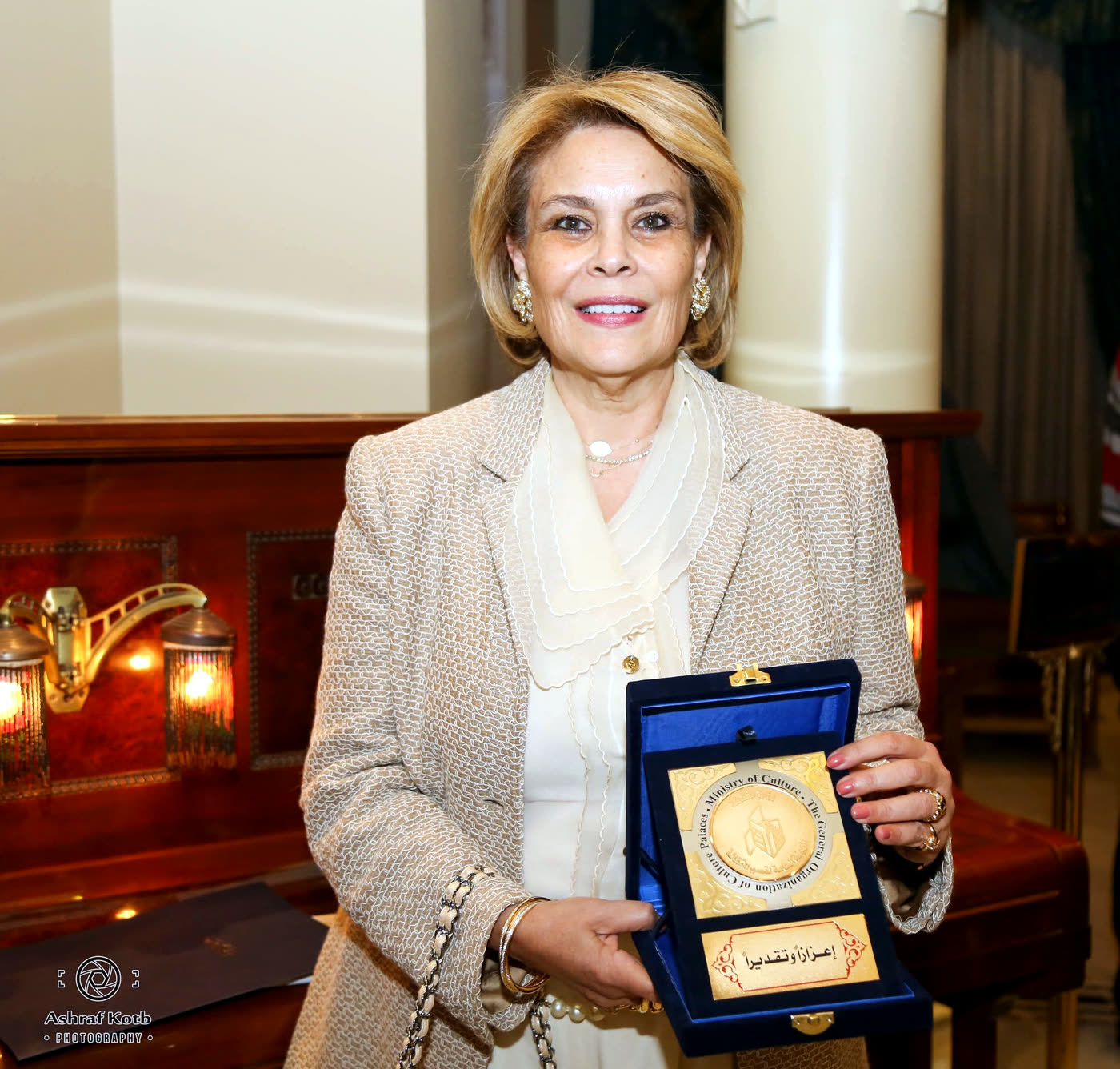 Rawya Mansour receiving recognition, holding an award plaque